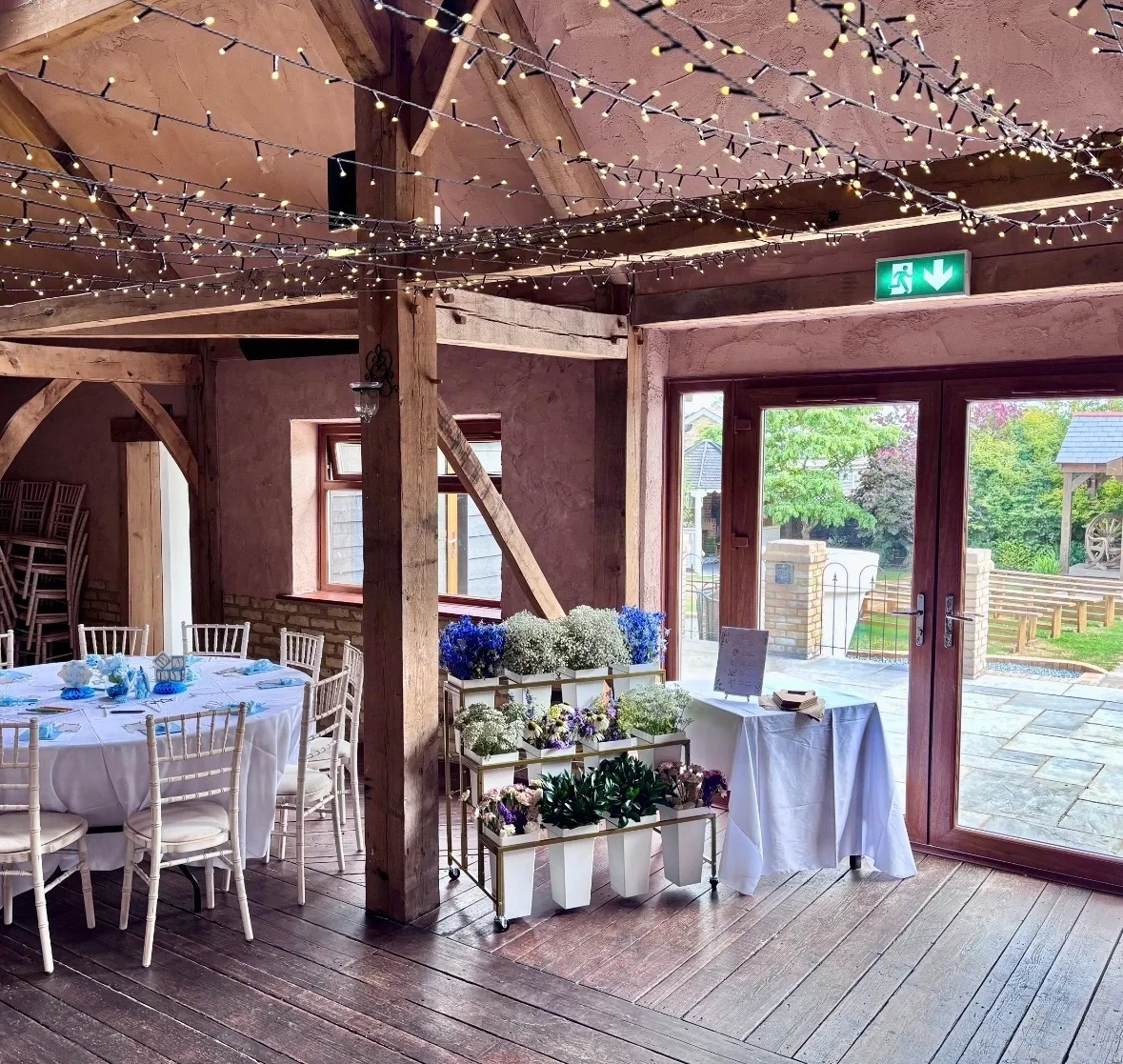 The Flower Bloom Bar set up in a beamed barn venue under fairy lights, beside a dressed table