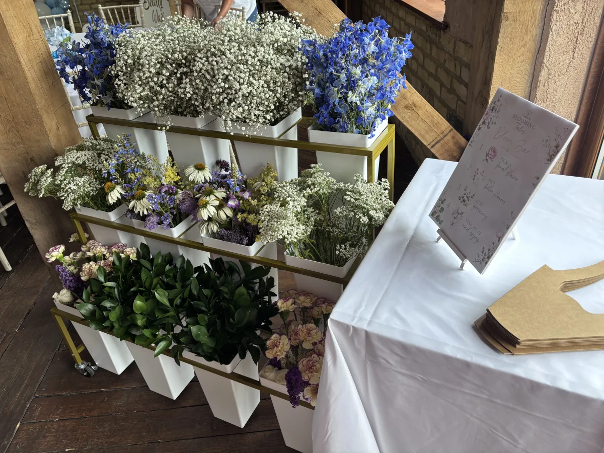 The Flower Bloom Bar cart stocked with delphiniums, gypsophila, echinacea, and foliage at a wedding venue